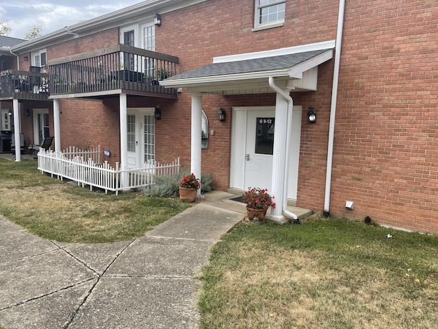 doorway to property featuring a balcony and a lawn