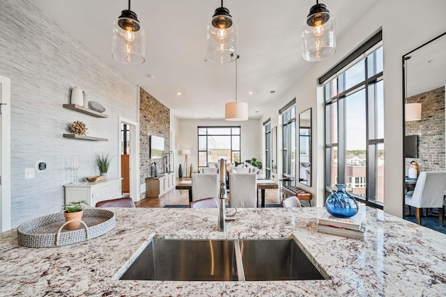 kitchen featuring decorative light fixtures, light stone counters, and sink