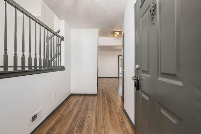 hall with a textured ceiling and hardwood / wood-style flooring