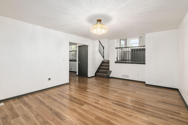 unfurnished living room with wood-type flooring and a notable chandelier