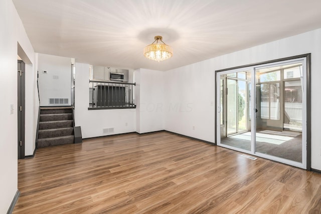 unfurnished living room featuring hardwood / wood-style floors and a chandelier