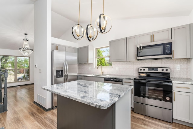 kitchen with a wealth of natural light, a center island, sink, and appliances with stainless steel finishes