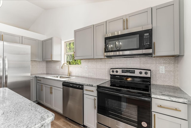 kitchen featuring gray cabinetry, backsplash, sink, vaulted ceiling, and stainless steel appliances