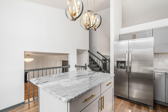 kitchen featuring gray cabinetry, a center island, decorative backsplash, stainless steel fridge, and light hardwood / wood-style floors