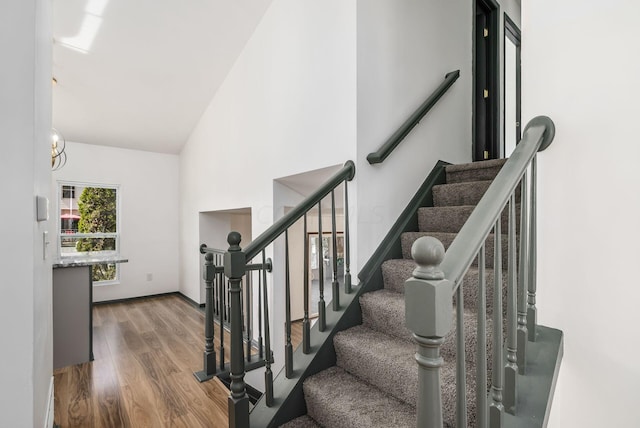 staircase with hardwood / wood-style flooring, an inviting chandelier, and lofted ceiling