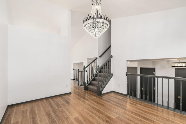 entrance foyer featuring a towering ceiling, hardwood / wood-style flooring, and a notable chandelier