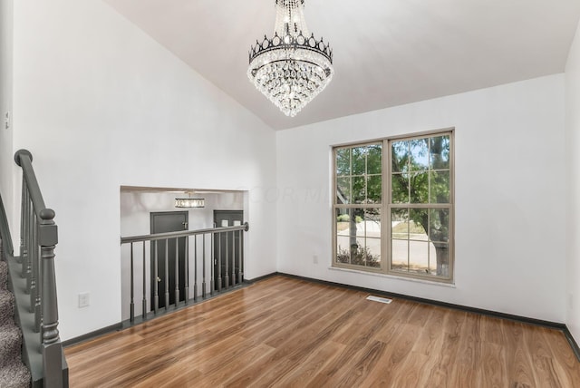 unfurnished living room featuring a chandelier, wood-type flooring, and vaulted ceiling