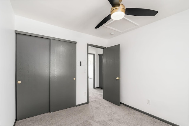 unfurnished bedroom featuring ceiling fan, light colored carpet, and a closet