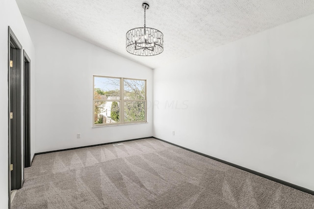 carpeted empty room featuring a textured ceiling, vaulted ceiling, and a notable chandelier