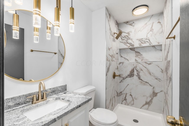 bathroom with vanity, toilet, and tiled shower