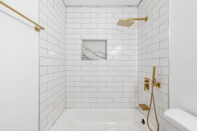 bathroom featuring toilet and tiled shower / bath