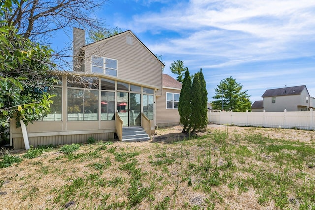 rear view of property featuring a lawn and a sunroom