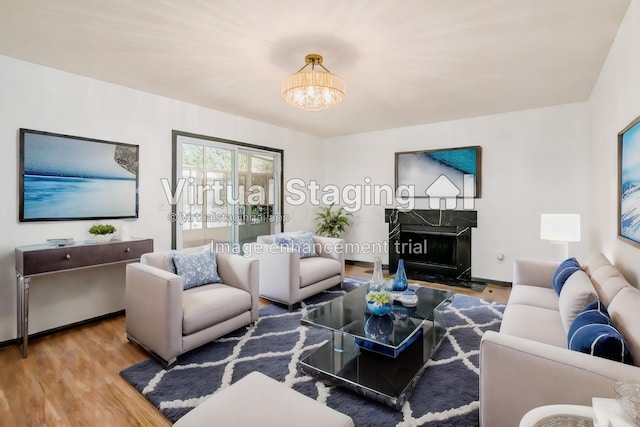 living room with a high end fireplace, wood-type flooring, and a notable chandelier