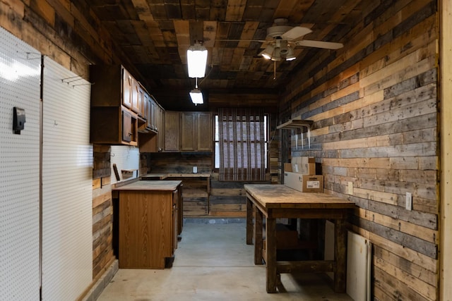 kitchen with pendant lighting, wooden ceiling, ceiling fan, and wood walls