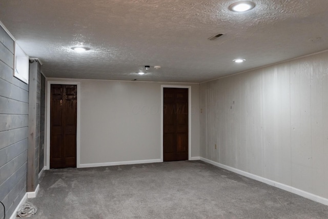 spare room featuring wooden walls, carpet flooring, and a textured ceiling