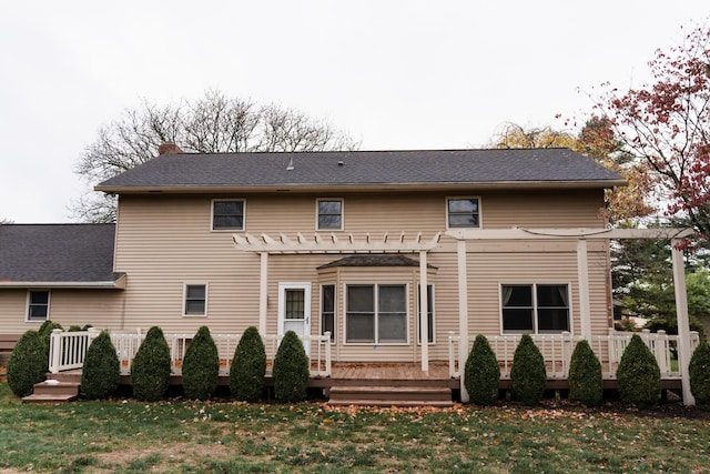 rear view of house with a pergola, a deck, and a lawn