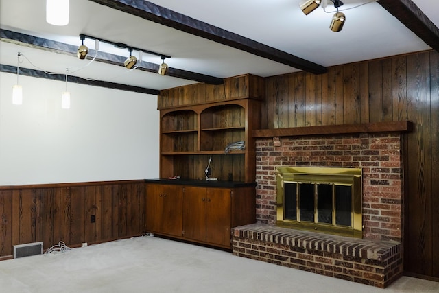 unfurnished living room with a brick fireplace, wooden walls, light colored carpet, and beamed ceiling