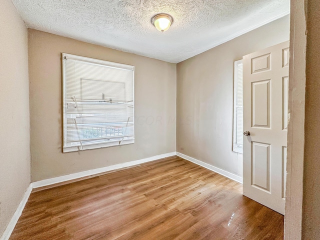 unfurnished room with hardwood / wood-style flooring and a textured ceiling