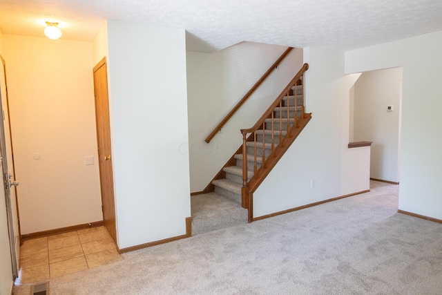 stairs with carpet floors and a textured ceiling