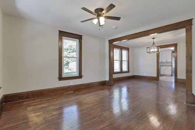 spare room with ceiling fan with notable chandelier and dark wood-type flooring