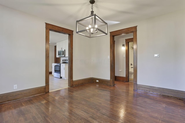 spare room featuring dark hardwood / wood-style flooring and a notable chandelier