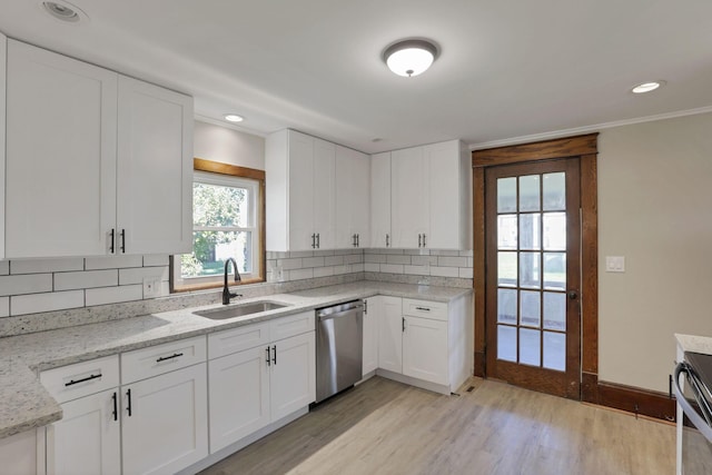 kitchen with sink, stainless steel appliances, tasteful backsplash, white cabinets, and light wood-type flooring