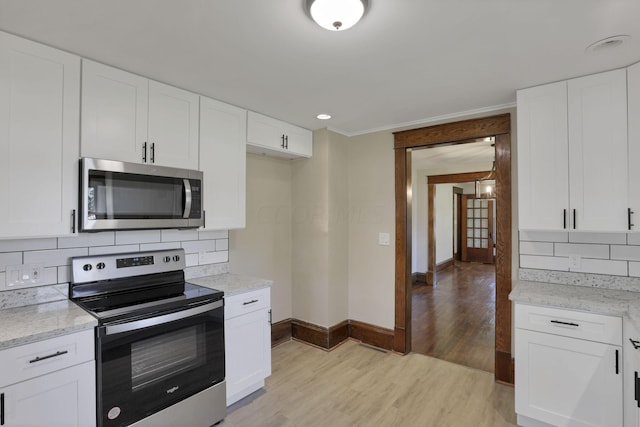 kitchen featuring white cabinets, decorative backsplash, light wood-type flooring, and stainless steel appliances