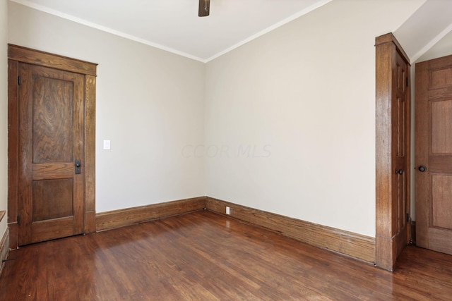 spare room with crown molding and dark wood-type flooring