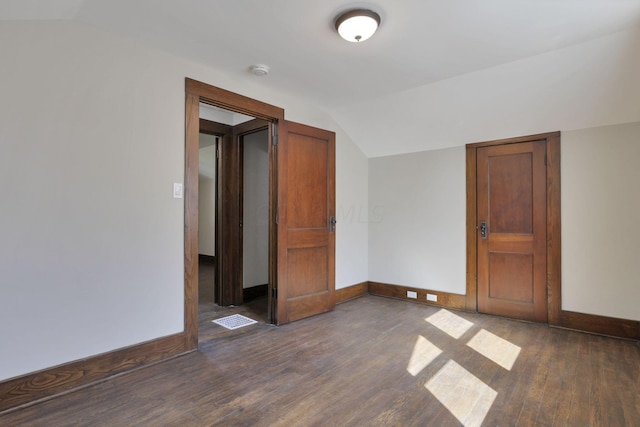 unfurnished room featuring dark wood-type flooring and lofted ceiling