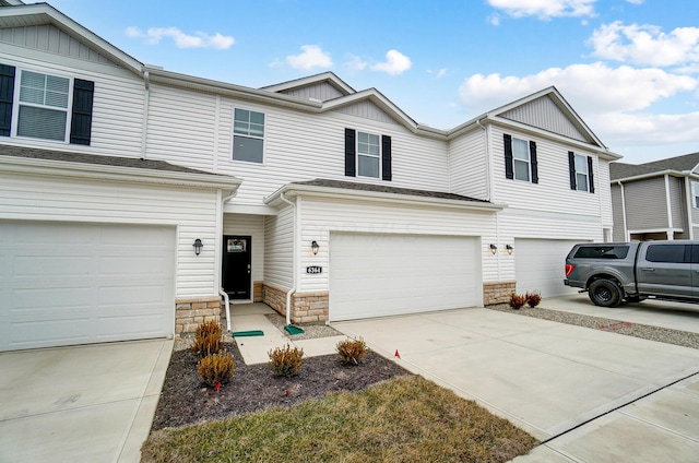 multi unit property with stone siding, a garage, and driveway