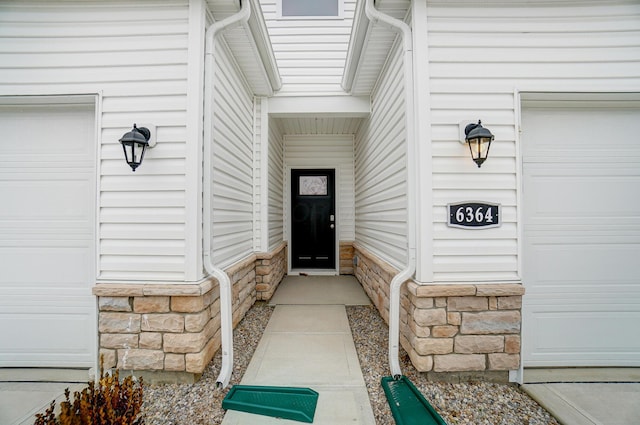 entrance to property featuring stone siding and a garage