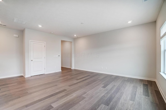 unfurnished room featuring recessed lighting, wood finished floors, and baseboards