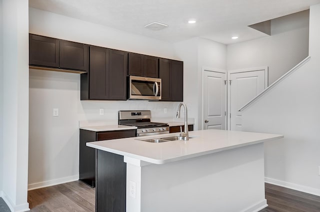 kitchen with dark wood-style flooring, stainless steel appliances, light countertops, and a sink