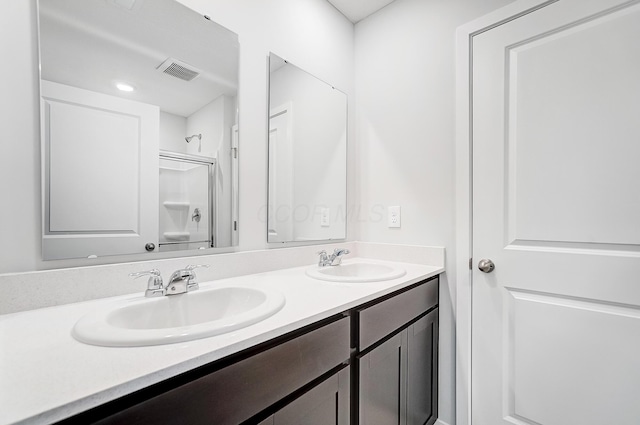 full bath with double vanity, walk in shower, visible vents, and a sink