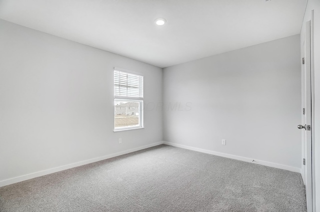 carpeted spare room featuring baseboards