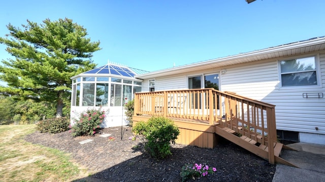 rear view of house featuring a sunroom and a deck