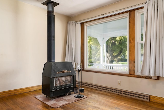 room details featuring hardwood / wood-style flooring, a wood stove, and a baseboard heating unit