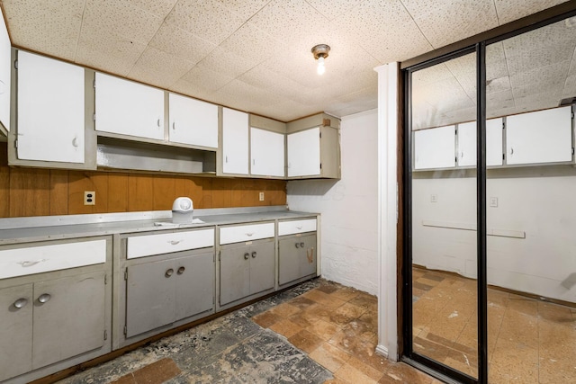 kitchen featuring wooden walls and white cabinets