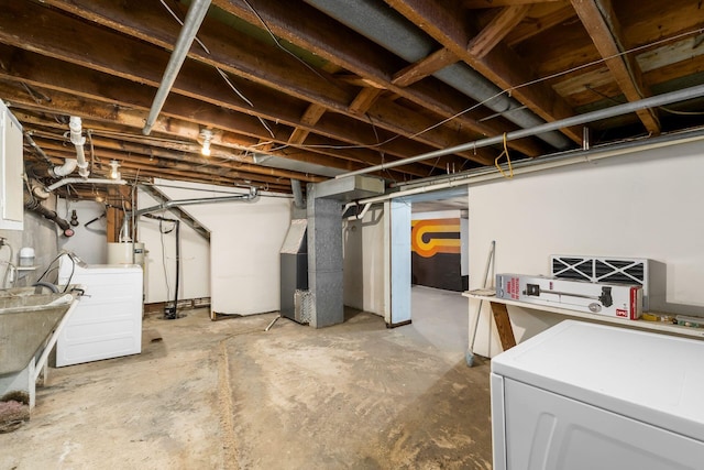 basement featuring heating unit, water heater, and washer / dryer