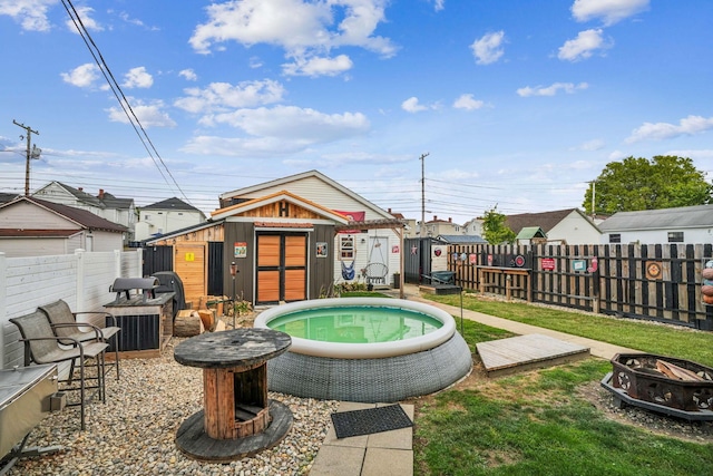 view of pool with a fire pit and an outdoor structure