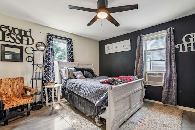 bedroom featuring hardwood / wood-style flooring, ceiling fan, and multiple windows