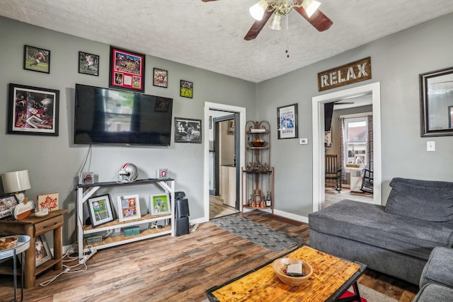 living room with hardwood / wood-style flooring, ceiling fan, and a textured ceiling