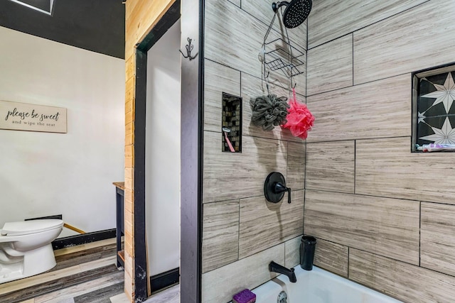 bathroom featuring tiled shower / bath combo, toilet, and wood-type flooring