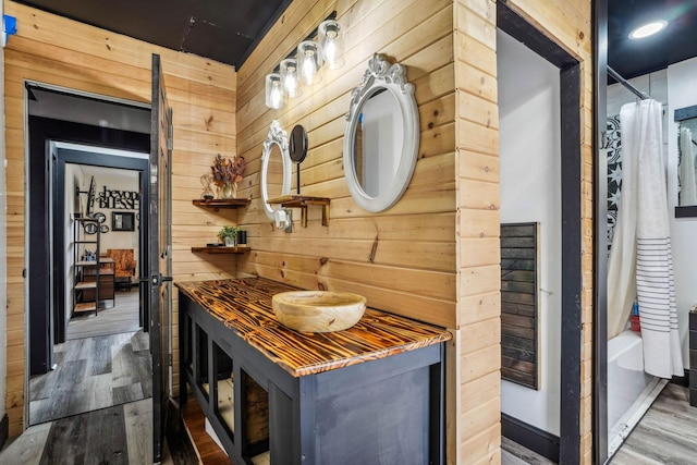 interior space featuring shower / bath combination with curtain, hardwood / wood-style flooring, and wood walls