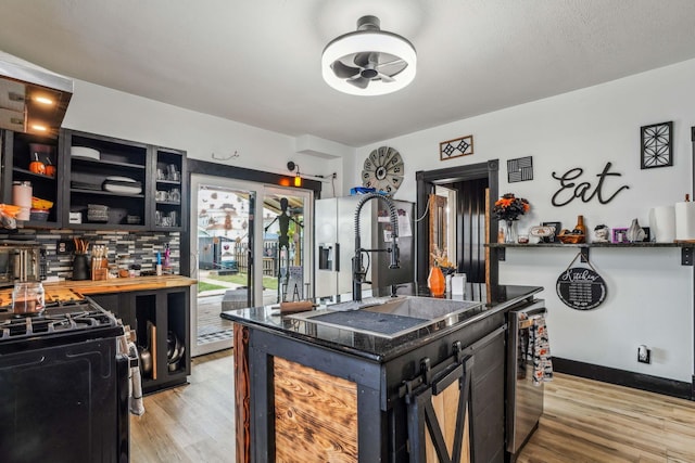 kitchen with black gas range, a center island, light hardwood / wood-style flooring, and sink