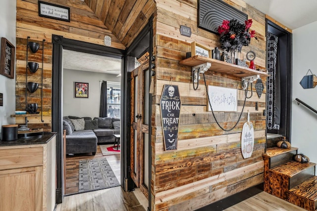 interior space featuring light hardwood / wood-style flooring, lofted ceiling, and wood walls