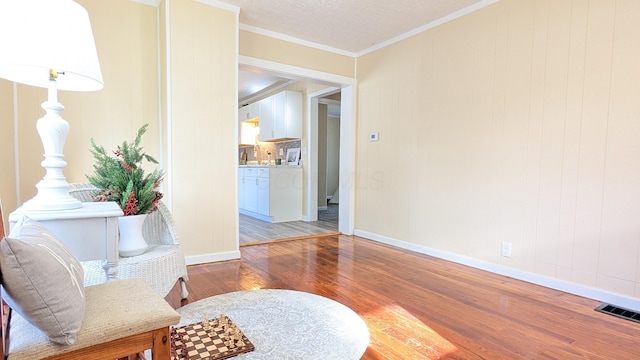 living area featuring hardwood / wood-style floors, a textured ceiling, and ornamental molding