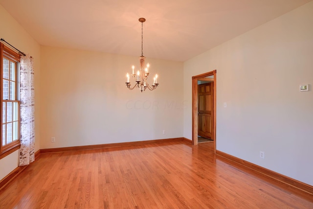 unfurnished room with a chandelier and light hardwood / wood-style floors