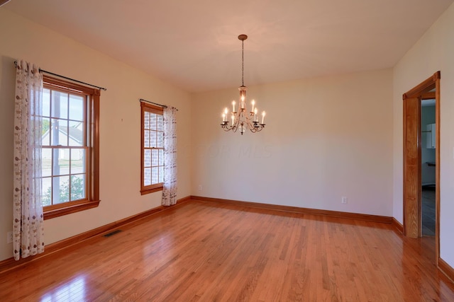 empty room featuring light hardwood / wood-style floors and a notable chandelier