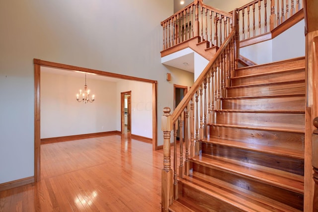 staircase with hardwood / wood-style floors, a high ceiling, and a notable chandelier